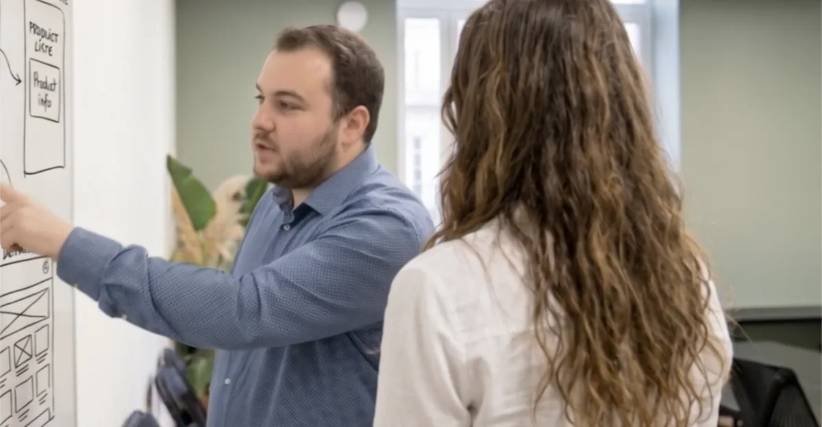 Deux membres de l’équipe cadrent un parcours devant un tableau blanc